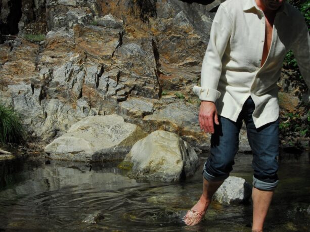 Man in wool shirt crossing stream